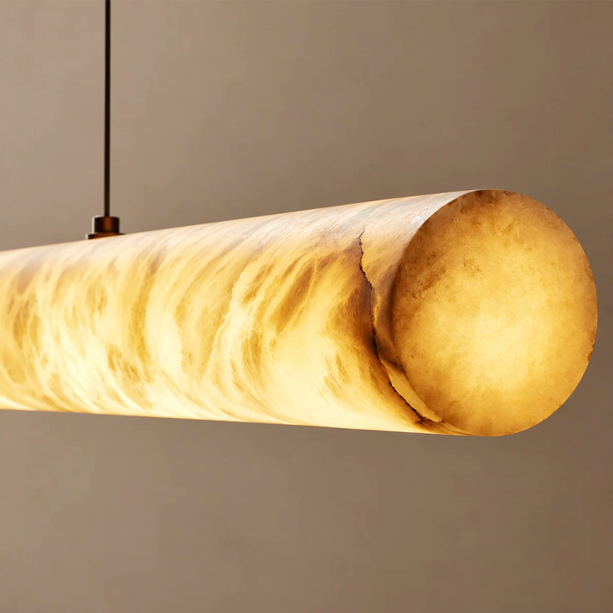 Close-up of the cylindrical alabaster pendant shade showing amber-toned veining when illuminated