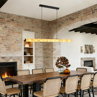 Linear alabaster pendant light suspended above a long wood dining table in a rustic dining room
