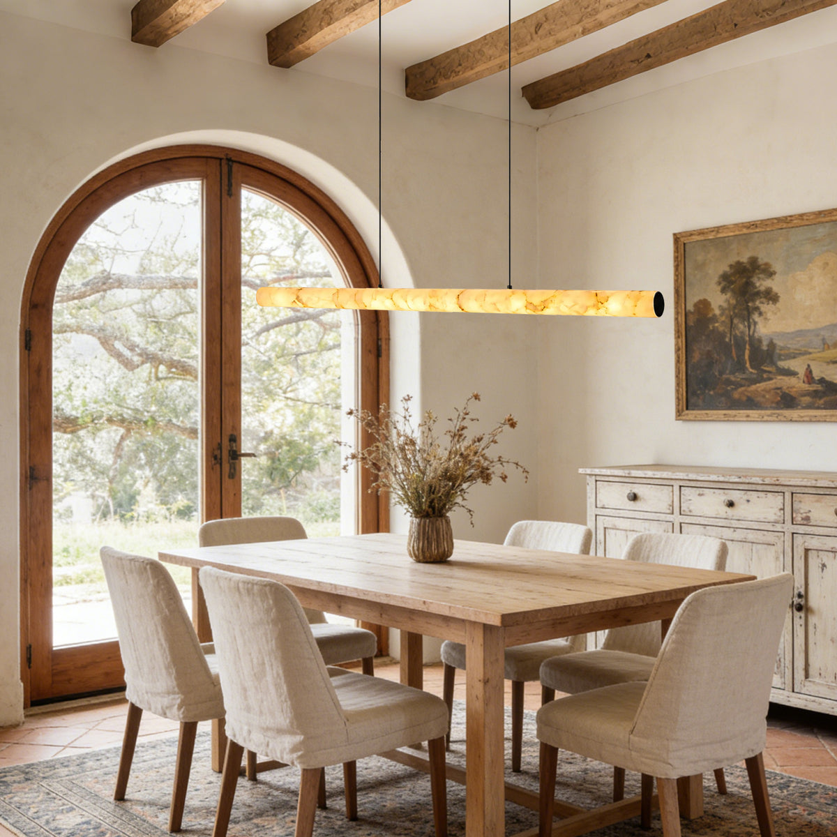 Glowing linear alabaster pendant above a wood dining table in a warm neutral interior