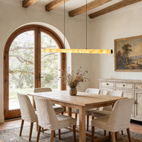 Glowing linear alabaster pendant above a wood dining table in a warm neutral interior