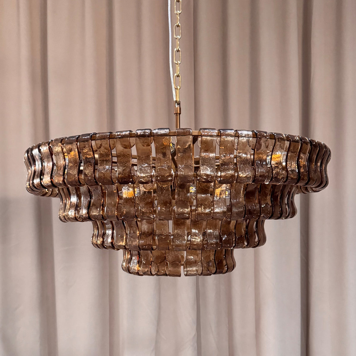 Smoke glass chandelier shown unlit with curved panels and brass finish frame